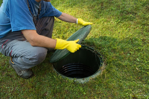 A man lifting up a septic tank lid.