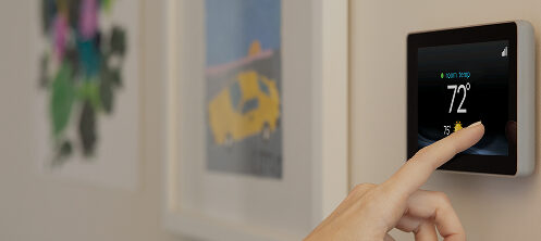 Woman's hand adjusting the temperature on a smart thermostat
