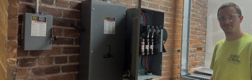 PGA Inc. electrician standing next to a circuit breaker