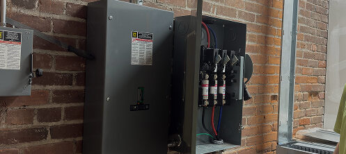 PGA Inc. electrician standing next to a circuit breaker