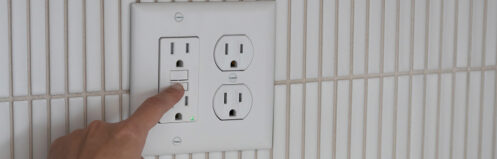 Hand pointing to an electrical outlet in Central Wisconsin