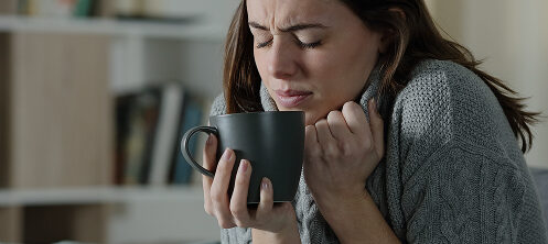 Woman bunched up from cold Wisconsin air while holding a coffee cup